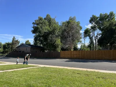 Parent teaching small child to ride bicycle on a suburban street.