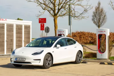 A Tesla Model 3 with a European license plate is connected to a Tesla Supercharger.