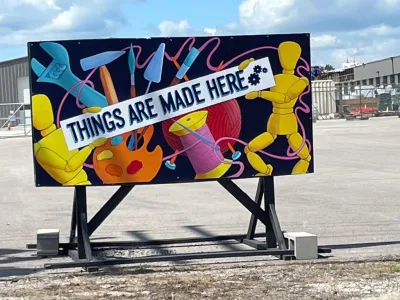 Mural showing tools and craft supplies with banner reading 'Things are made here' in front of makerspace in Columbia, Missouri.