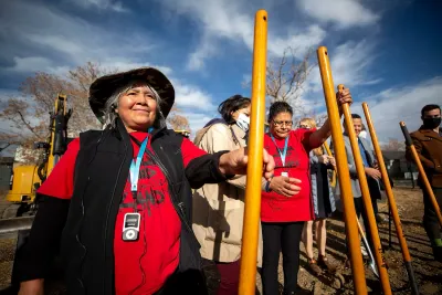 People in red shirts holding shovels for photo op at groundbreaking for community land trust project in Denver.