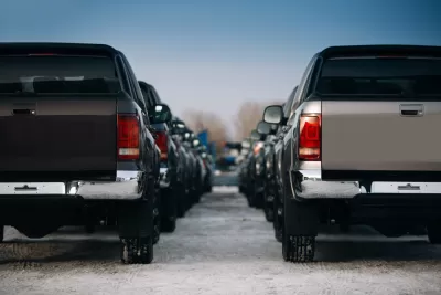 Large pickup trucks are parked in neat rows extending into the fuzzy background of the image.