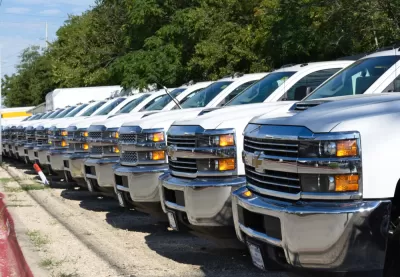 A row of white pickup trucks at a car dealership.