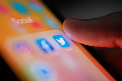 A person’s thumb hovers over the Twitter app on a smart phone.