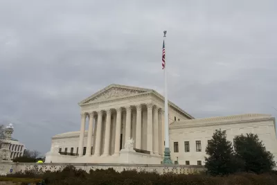 The exterior of the U.S. Supreme Court, with an American flag flying above its large columns and white marble exterior.