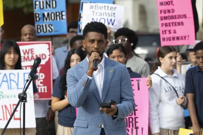 The mayor of Baltimore speaks into a microphone in front of a rally for more state transportation funding from Maryland. 