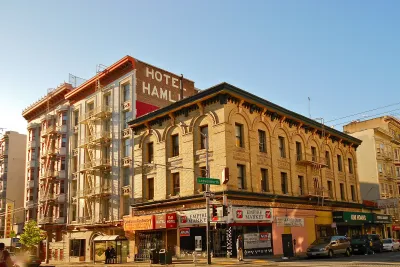 Mid-rise vintage SRO brick hotel building with ground floor retail and "Hotel Hamlin" painted sign on side in Tenderloin district, San Francisco.
