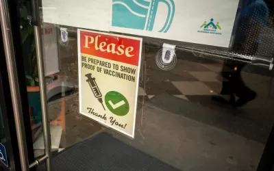 A sign on a door says proof of vaccine is required to enter.