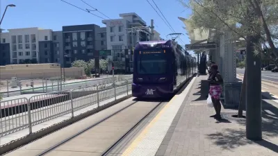 Purple Phoenix light rail train pulling into outdoor station.