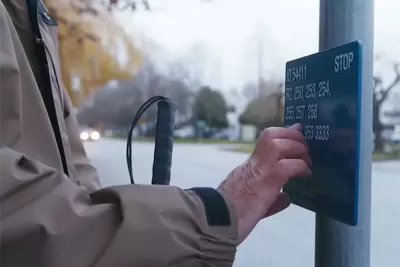 Close-up of hand reading Braille sign at bus stop in Vancouver, British Columbia.