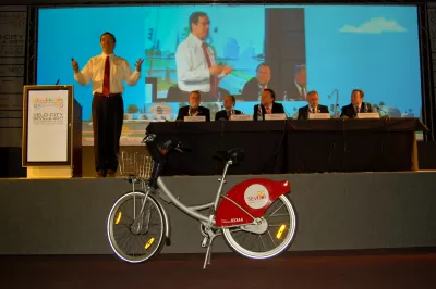 Gil Penalosa speaking on a stage at Velo-city conference in Seville, Spain, with bicycle in foreground