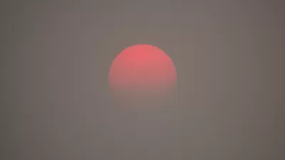 A red sun appears on the horizon, as obscured by haze from wildfire smoke.