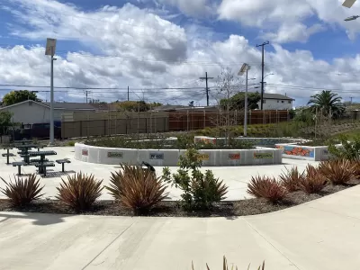 Concrete walkway with landscaping, decorative tiles, and picnic tables in a Los Angeles County park.