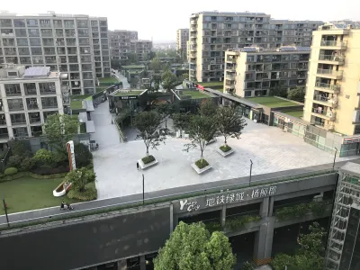 Complex of high-rise apartment buildings around a concrete plaza with several large trees in China.