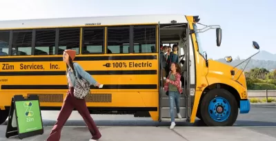 Yellow electric school bus with preteen students exiting.