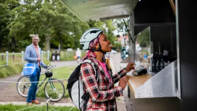 People with bikes ordering at food trucks outdoors.