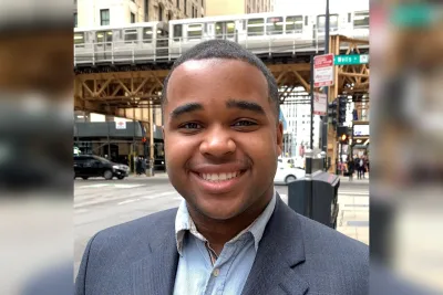 Head shot of smiling young man standing on busy urban street.