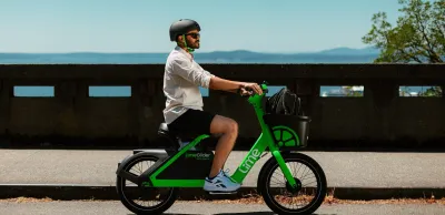 Man riding LimeGlider green shared mobility pedal-less e-bike/scooter hybrid.