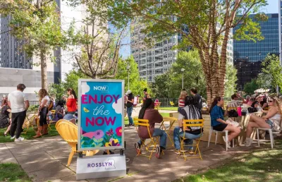 Pop-up park with people sitting at yellow outdoor furniture.