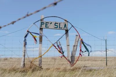 A sign reading Pe’ Sla in a grassy prairie.