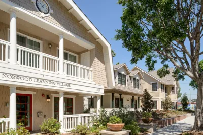 Row of light-colored craftsman homes, part of Norwood Learning Village teacher housing in Los Angeles.