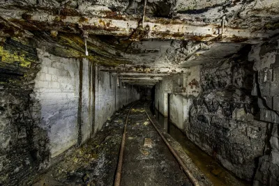An abandoned mine in Pennsylvania. The ceiling is low, the walls and floors are gray, and mine cart tracks run along the bottom.