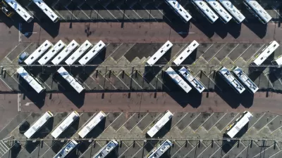 Aerial view from directly overhead of buses parked in large asphalt lot