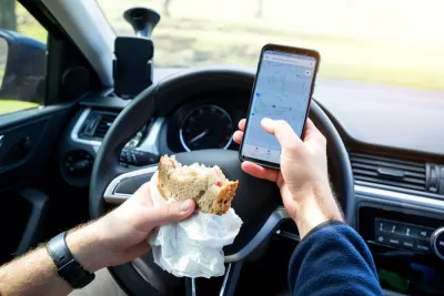 Close-up of person eating sandwich and texting while driving