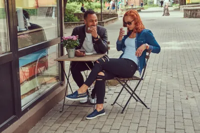 Young couple sitting at a small sidewalk cafe table.