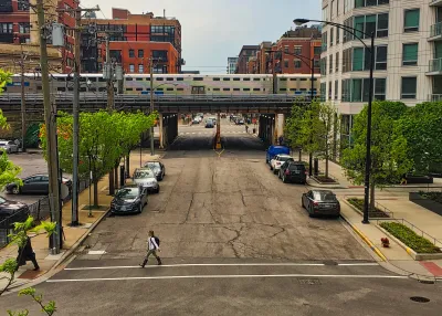 Chicago elevated train passing over street with parked cars.