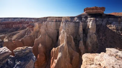 A picture of Coalmine Canyon, a rust-colored canyon under a blue sky.