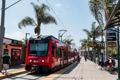 A red San Diego trolley car stopped at a platform with people waiting in San Ysidro, California near the Mexico border.