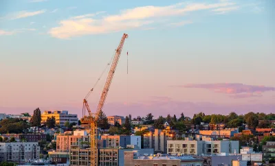 Seattle skyline in low-rise area with yellow construction crane rising over buildings at dusk.