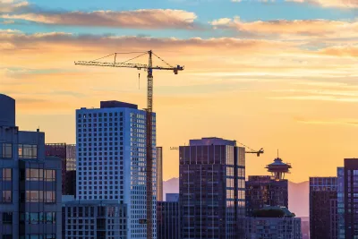 Construction crane against downtown Seattle skyline at sunset.