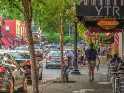 Person walking down wide sidewalk next to restaurant patio tables in Chagrin Falls, Ohio.