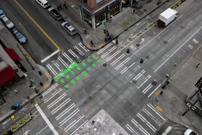 An almost empty intersection in downtown Seattle Washington. An arial shot off of the side of a building that shows the crisscrossing of roads, crosswalks, and bike lanes.