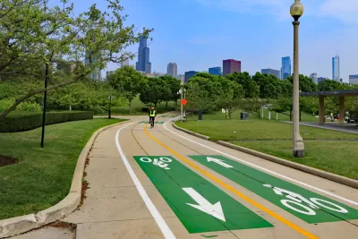 Paved two-way bike trail with yellow center line, green paint, and Chicago buildings inbackground