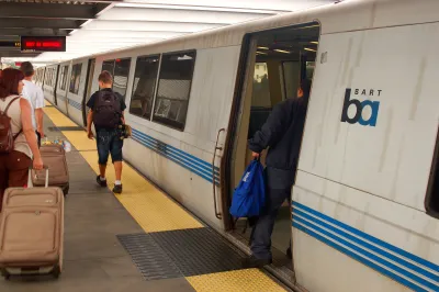 People boarding a white BART train at a platform.