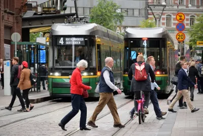 Busy Helsinki street with pedestrians and green streetcars.