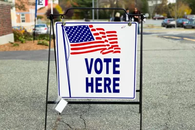 "Vote Here" sidewalk sign with American flag