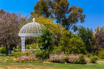 White gazebo among green plants and trees at botanical garden