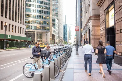 Divvy bike share station in Chicago with people checking out blue bikes.