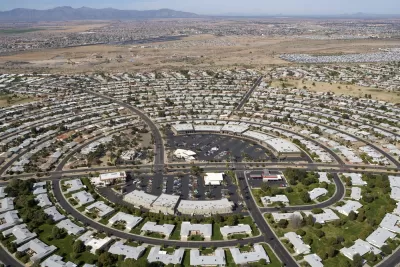 Aerial view of circular street pattern with buildings in Sun City, Arizona with desert mountains in background