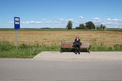 Woman sitting on bench at rural bus stop