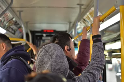 Bus riders standing on crowded city bus, holding top rail
