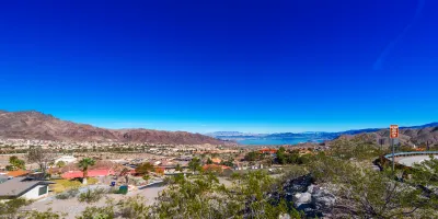 View of the mountain landscape near Boulder, Nevada. A town filled with houses with orange roofs is surrounded by mountains.