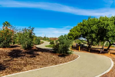 Concrete walking and biking trail winding through trees and bushes