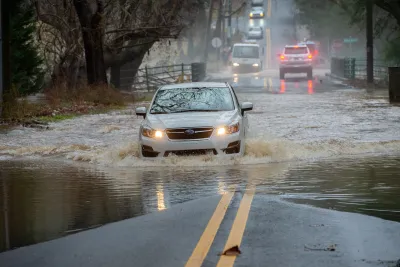 White car driving on flooded street.