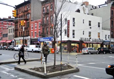 New York City intersection with red and white brick buildings and pedestrians.