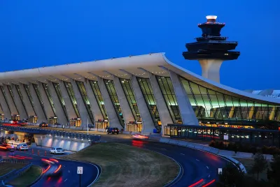 Terminal at Dulles Airport with control tower behind it at dusk.