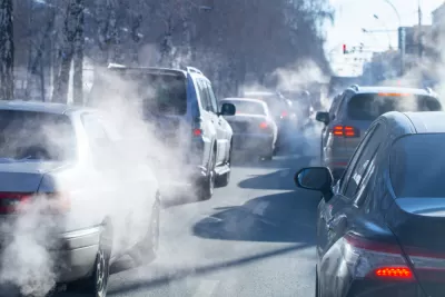 View of cars in traffic from behind with visible tailpipe emissions